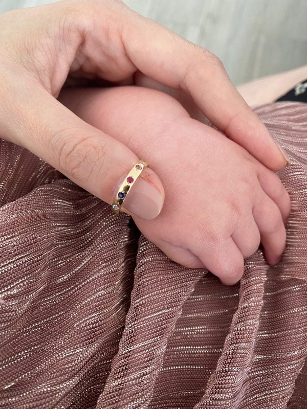 Anillo Birthstones estilo Family ring en mano de mama con bebe